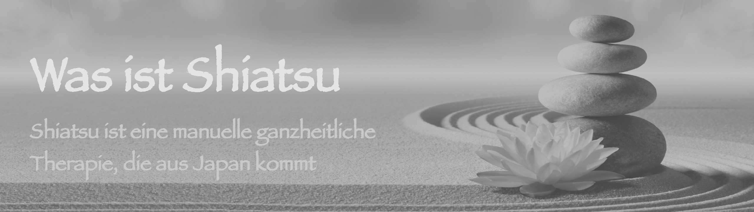 Spa-Steine und eine Lotusblüte auf sandigem Boden. Was ist Shiatsu? Shiatsu ist eine manuelle ganzheitliche Therapie, die aus Japan kommt.